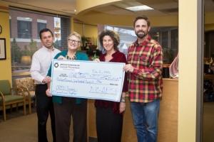 Counseling and Psychological Services Center staff hold up giant check for suicide prevention program